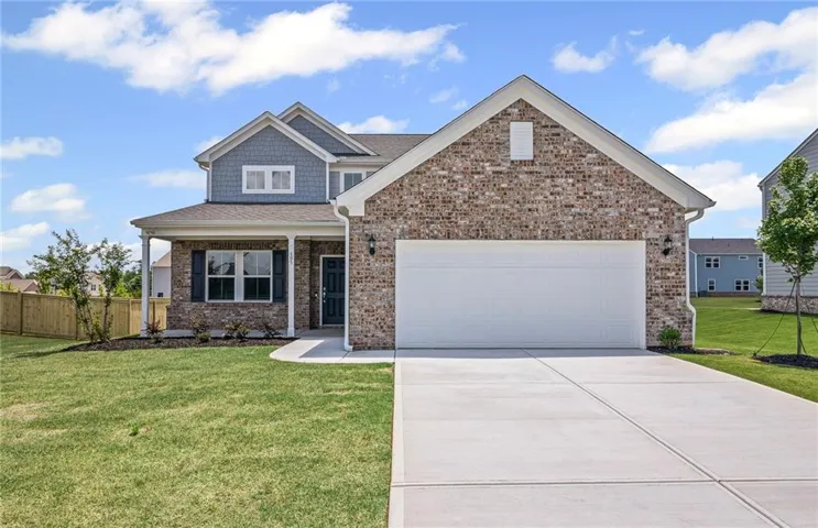 Brick and siding exterior featuring a covered porch with white columns, a two-car garage, and a concrete driveway