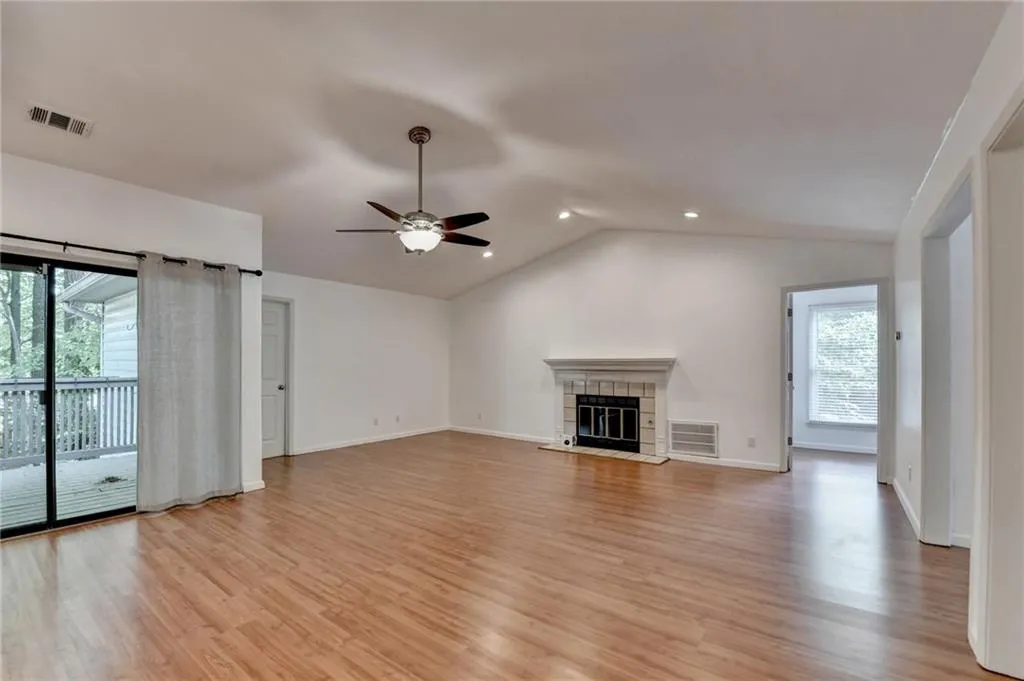 Unfurnished living room featuring vaulted ceiling, a tile fireplace, light wood-style floors, a ceiling fan, and recessed lighting