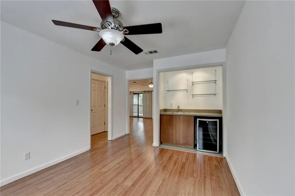 Bar area with wine cooler, light wood-style flooring, a ceiling fan, and brown cabinetry