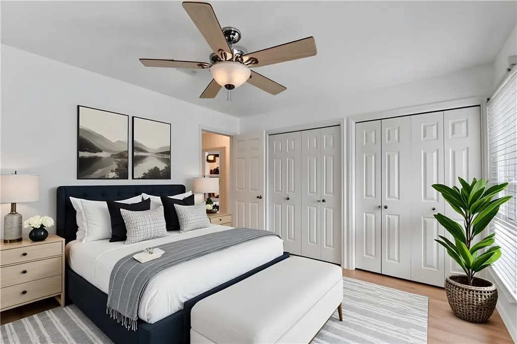 Bedroom featuring multiple closets, light wood-style flooring, and ceiling fan