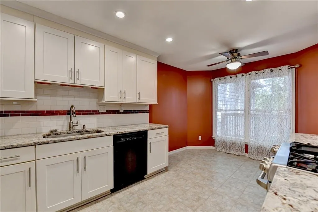 Kitchen featuring stainless steel gas stove, light stone counters, white cabinetry, dishwasher, and recessed lighting