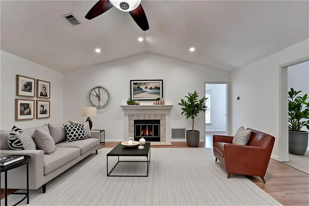 Living area with a tile fireplace, light wood-style floors, recessed lighting, a ceiling fan, and lofted ceiling