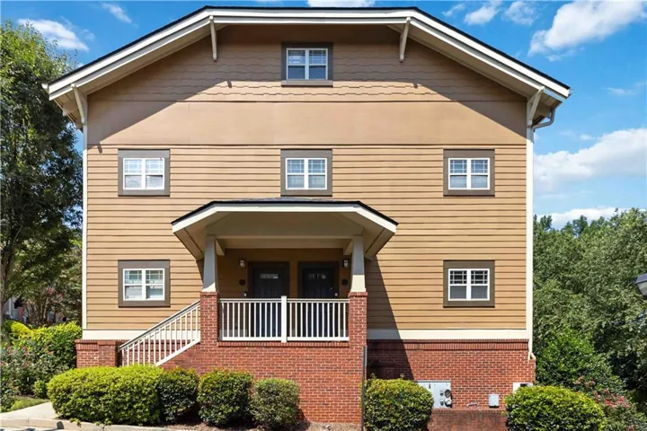 Siding exterior featuring a covered porch, white railing, and brick foundation