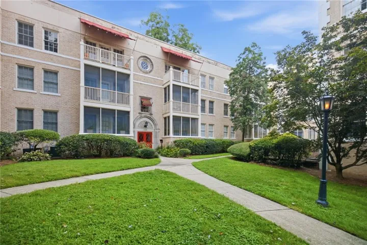 Brick exterior building featuring red awnings and screened balconies