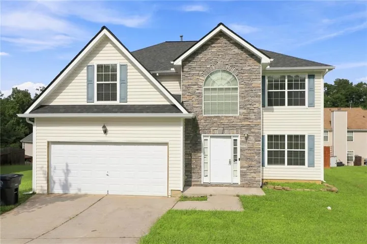 Stone facade accent, arched window, attached two-car garage, light-toned siding, and gabled roofline