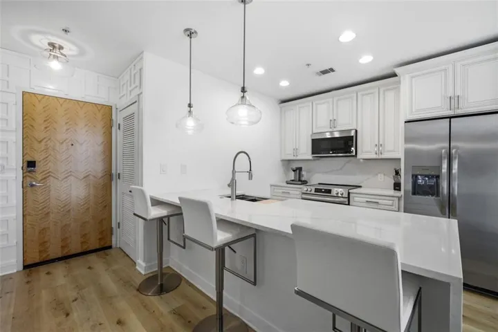 Kitchen featuring stainless steel appliances, built-in microwave, white shaker-style cabinetry, and a center island with pendant lighting