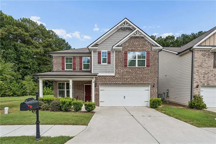 Brick and siding exterior with red shutters, a covered front porch, and an attached two-car garage