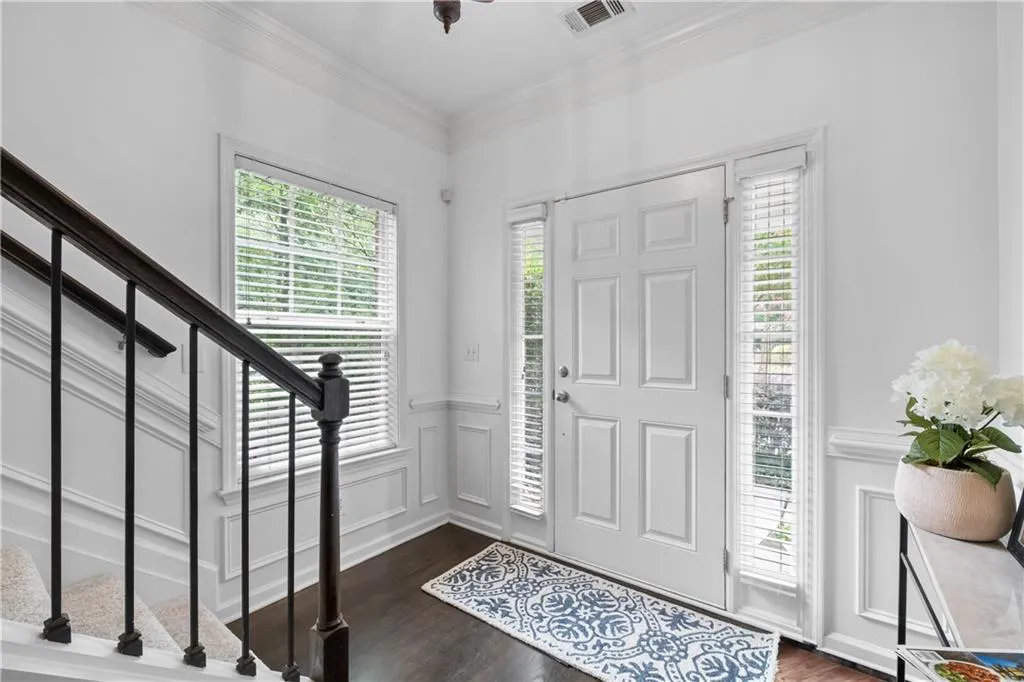 Spacious, bright, and inviting entryway with hardwood floors, natural light and architectural details