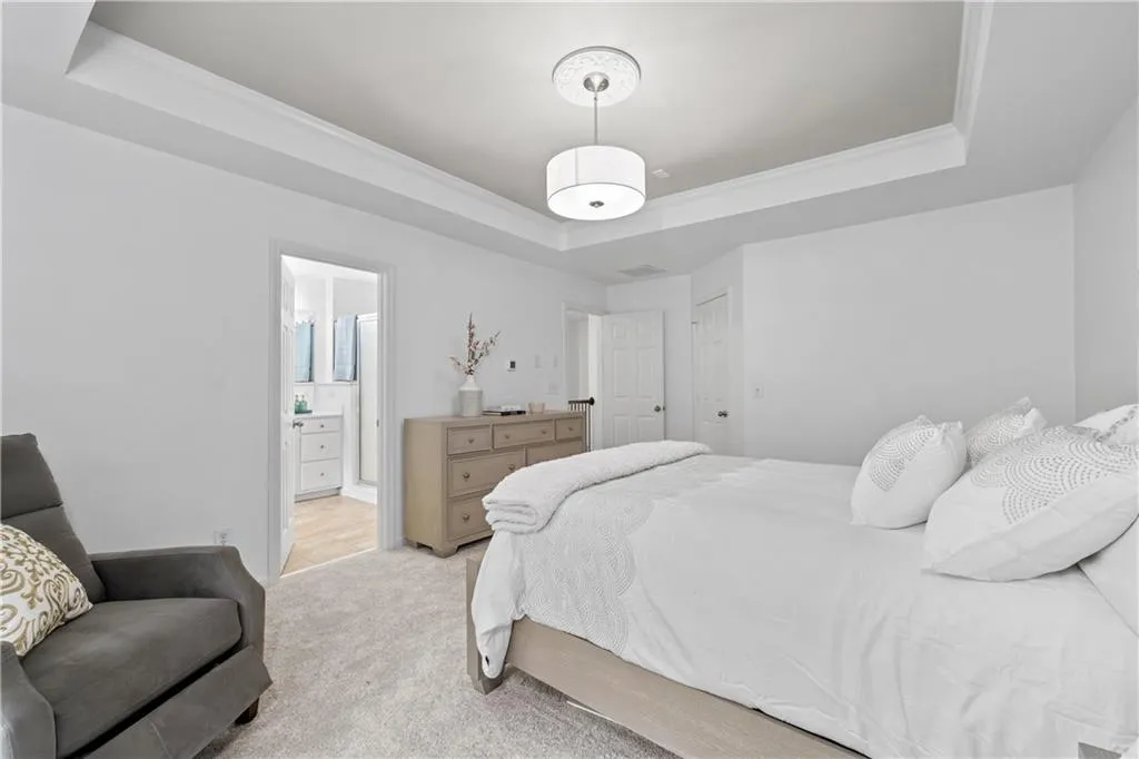 Spacious primary bedroom layout with abundant natural light, neutral color scheme, tray ceiling, crown molding, and ensuite bath.