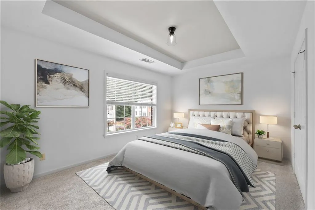 Virtually staged second floor ensuite featuring a trey ceiling, light carpet and large expansive window bringing in natural light.