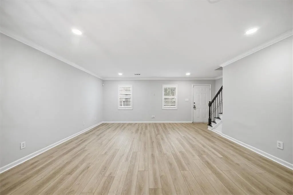 Unfurnished living room with light wood-style flooring, stairway, recessed lighting, and crown molding