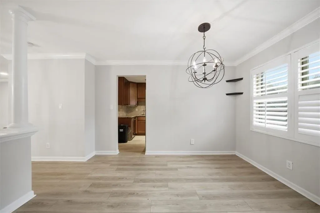 Unfurnished dining area with ornamental molding, light wood-style flooring, and a chandelier