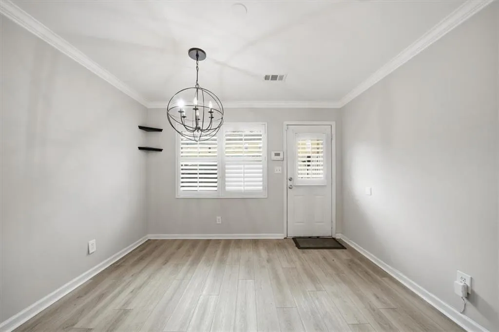 Unfurnished dining area with light wood-style floors, a chandelier, and crown molding