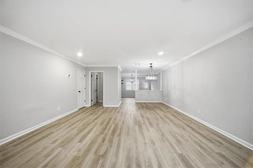 Unfurnished living room featuring light wood finished floors, recessed lighting, ornamental molding, and a chandelier