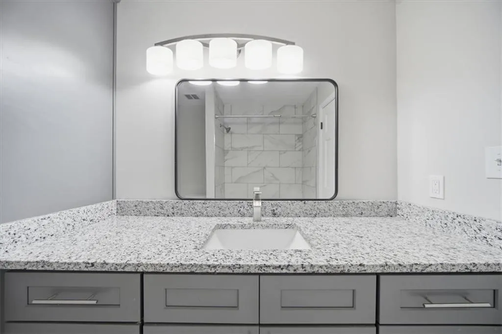 Full bath featuring tiled shower and vanity