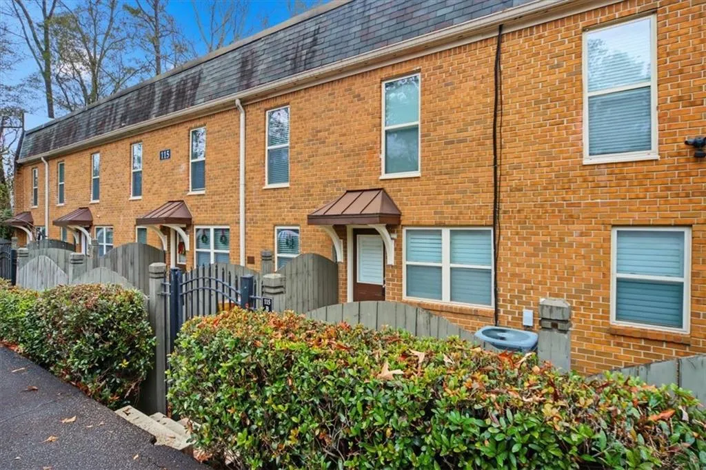 View of front of home featuring a fenced front yard, a gate, mansard roof, roof with shingles, and brick siding