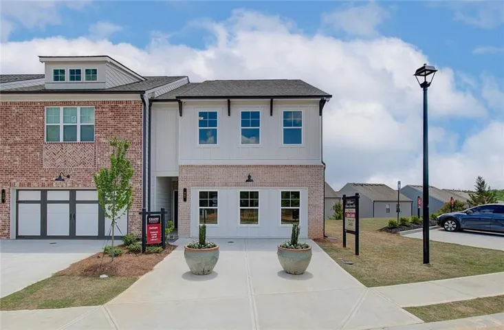 View of front of home featuring brick siding, concrete driveway, a garage, and board and batten siding