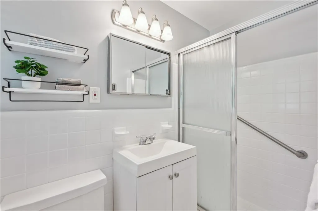Bathroom featuring vanity, a stall shower, tile walls, and a wainscoted wall
