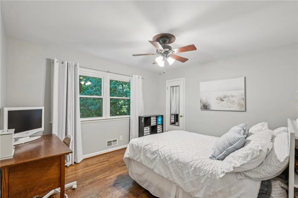 Bedroom with wood finished floors, a ceiling fan, and an office area