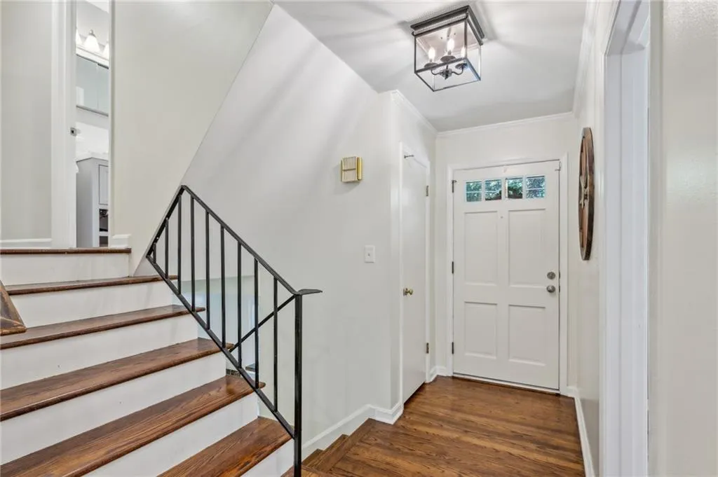 Foyer entrance featuring dark wood-type flooring, stairs, crown molding, and a chandelier