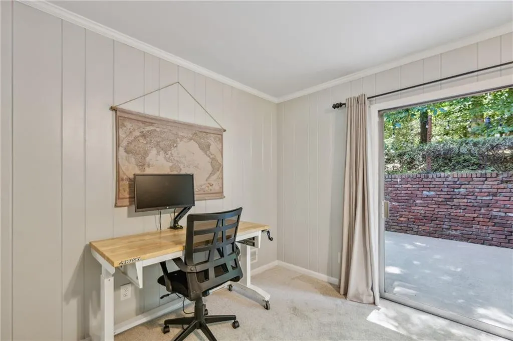 Carpeted office space with crown molding and baseboards with backyard access