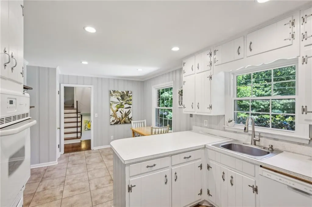 Kitchen with light countertops, a peninsula, white cabinetry, white appliances, and recessed lighting