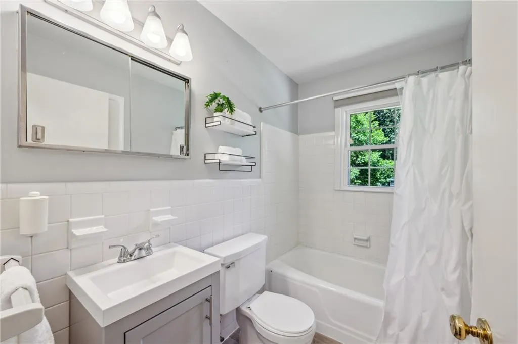 Bathroom with tile walls, vanity, shower / tub combo, and a wainscoted wall