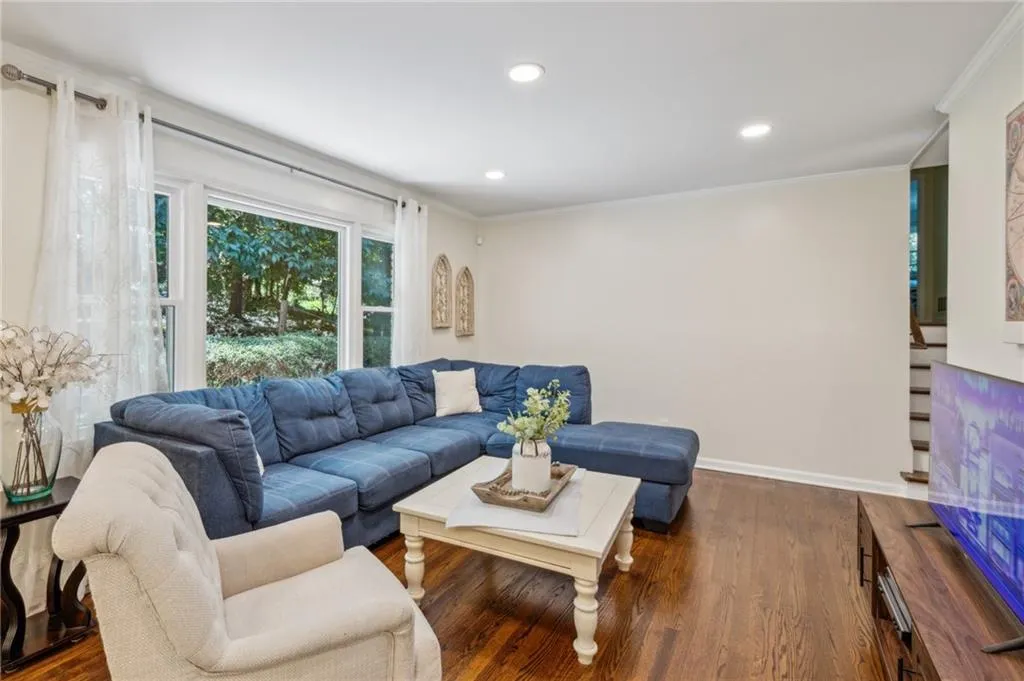 Living room featuring wood finished floors, ornamental molding, recessed lighting, and stairway