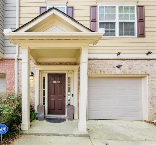 Entrance to property featuring a garage, driveway, and brick siding
