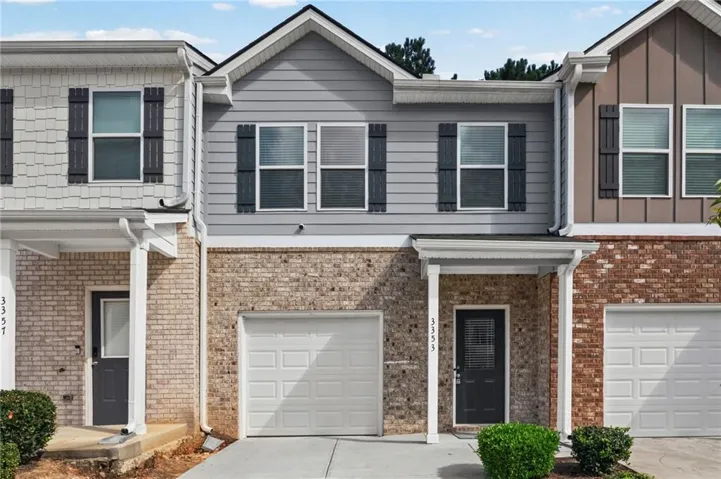 Brick and siding exterior with a covered entry, attached garage, and multiple windows with shutters