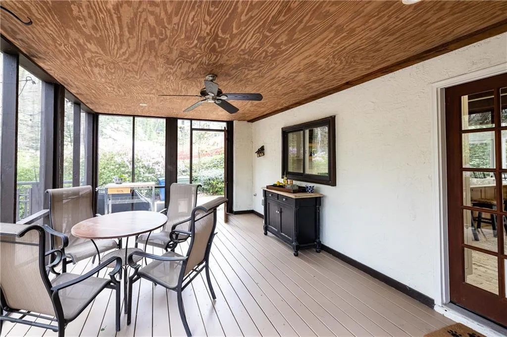 Sunroom / solarium featuring outdoor dining space, a textured wall, wood ceiling, ceiling fan, and wood-type flooring