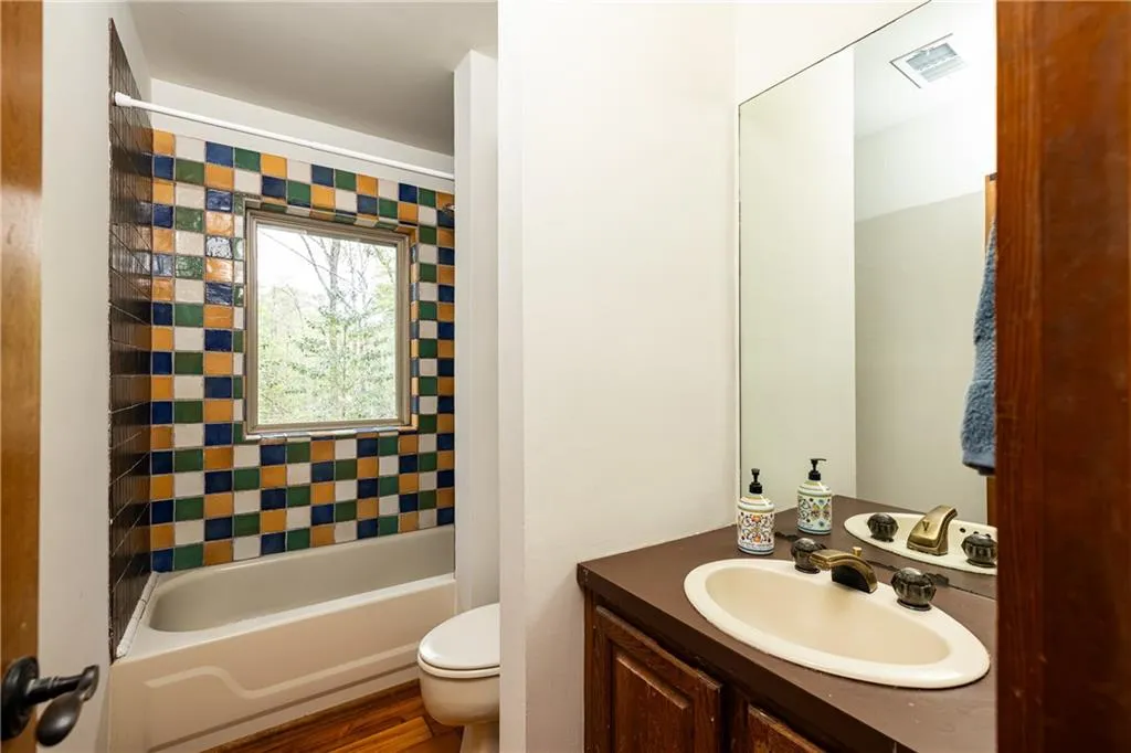 Bathroom featuring vanity, dark wood-type flooring, and bathing tub / shower combination