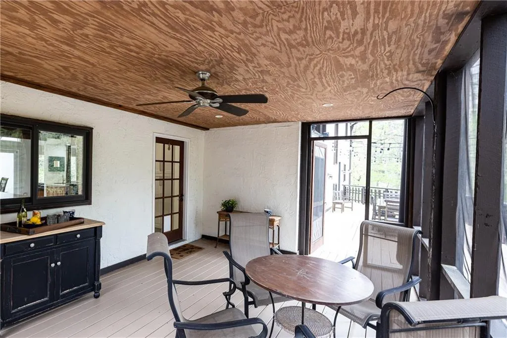 Dining space with a textured wall, ceiling fan, light wood-style floors, wooden ceiling, and plenty of natural light