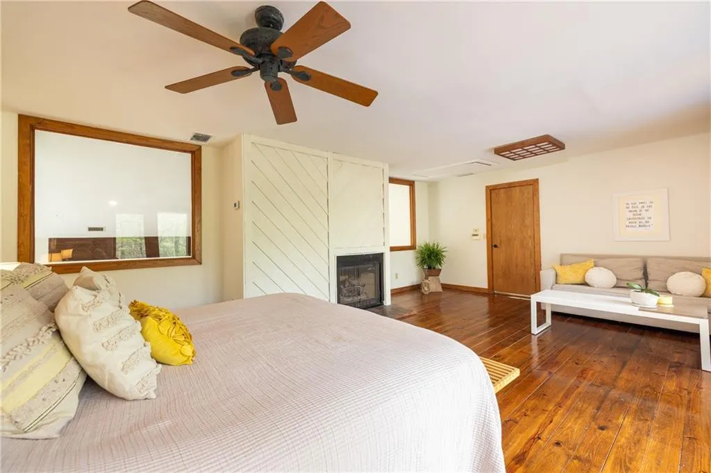 Bedroom featuring dark wood-type flooring, ceiling fan, and a fireplace