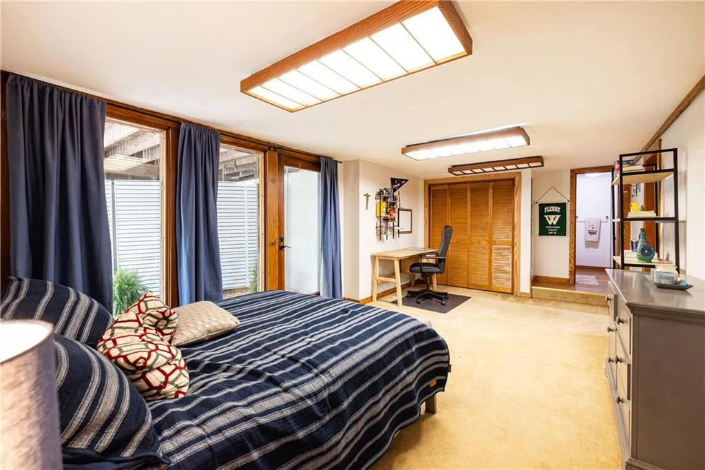 Bedroom featuring a desk, light colored carpet, and a closet
