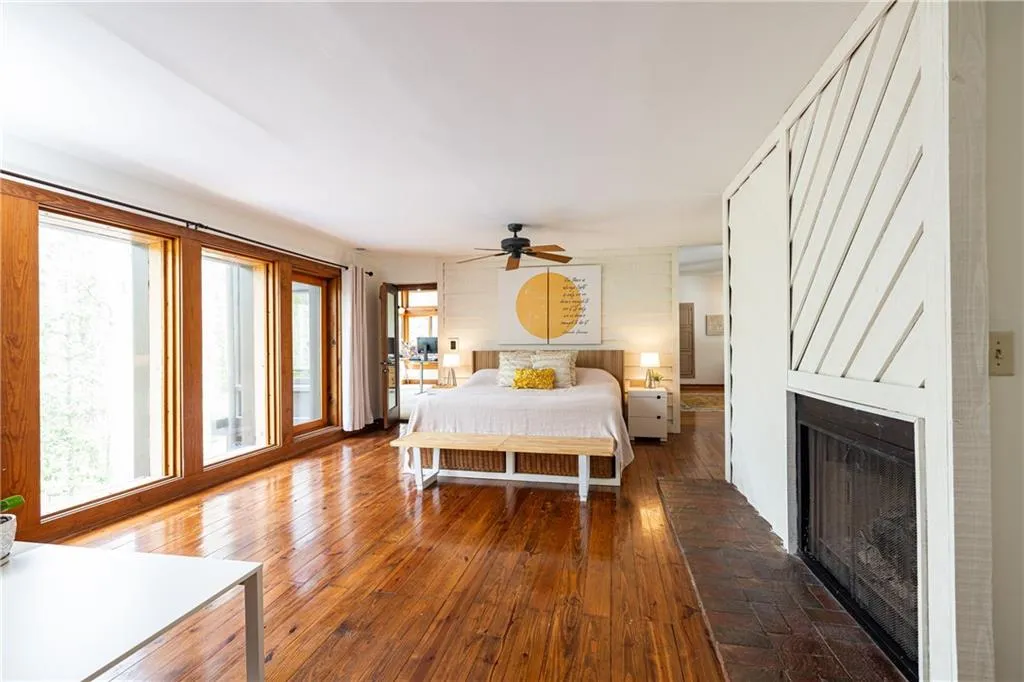 Bedroom with hardwood / wood-style flooring, a ceiling fan, and a fireplace