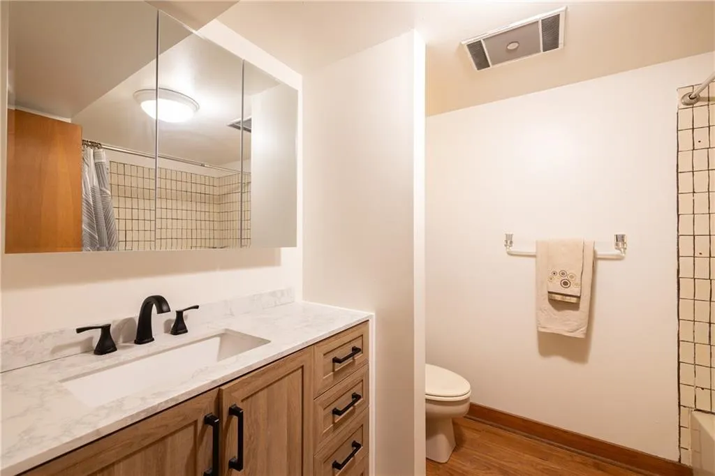 Full bath featuring a shower with shower curtain, vanity, and light wood-style floors