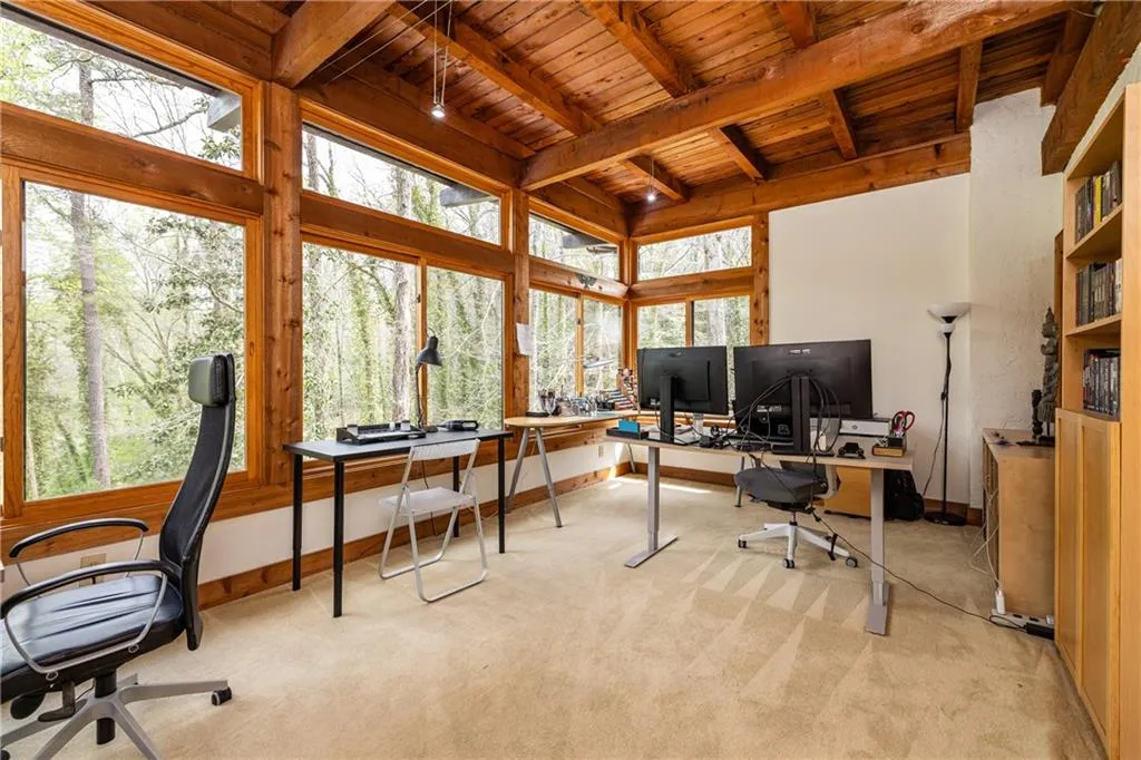 Office space with a wooden ceiling with exposed beams and light carpet