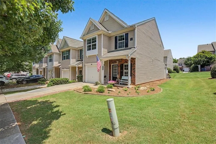 Two-story residence featuring light-colored siding and a brick-accented front porch