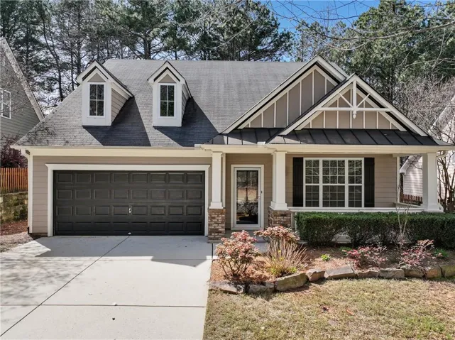 View of front of house with a porch, driveway, board and batten siding, an attached garage, and a shingled roof