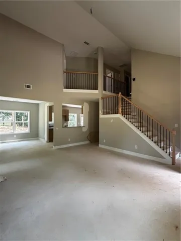 Two-story foyer with a vaulted ceiling, open staircase featuring wood handrails and black iron balusters, and a second-story landing overlooking the main level