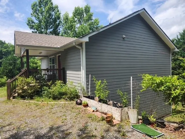 Exterior featuring gray horizontal siding, a covered front porch with dark wood railings and posts, and a dark brown front door