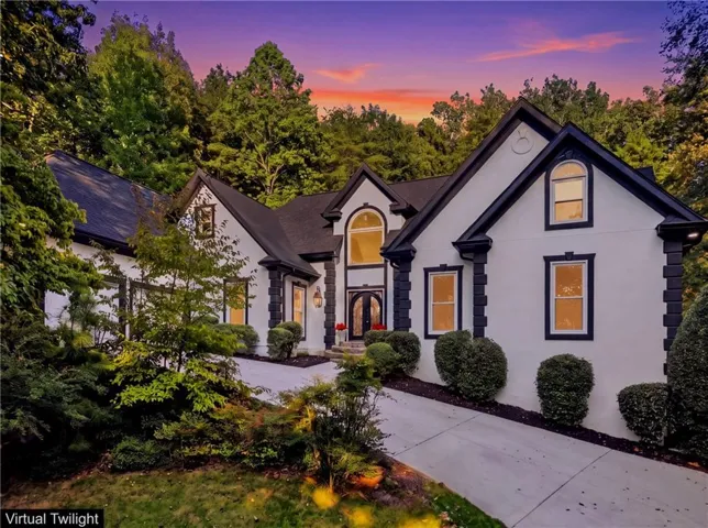 Stucco exterior with prominent black trim, gabled roofline, arched window, and double entry doors