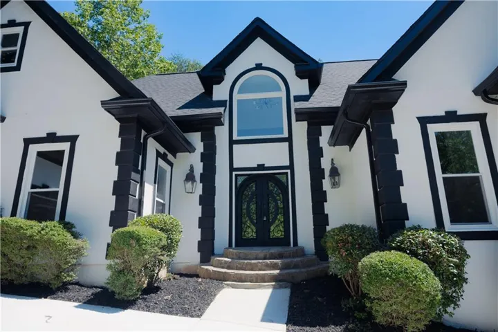 Stucco exterior with black trim accents and a prominent arched window