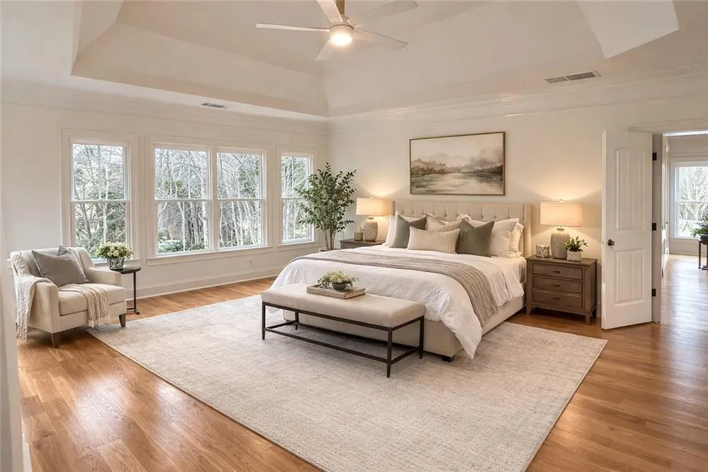 Bedroom featuring a ceiling fan, wood finished floors, ornamental molding, and a raised ceiling
