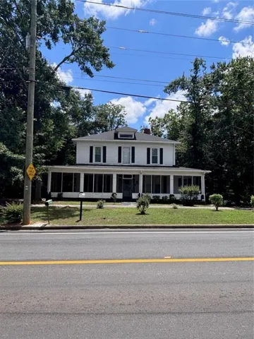 Two-story white residence featuring a screened-in porch, dormer window, and dark window shutters