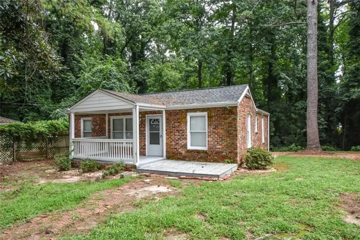 Brick exterior with white trim, featuring a covered front porch with white railings, a concrete front patio, and a shingle roof