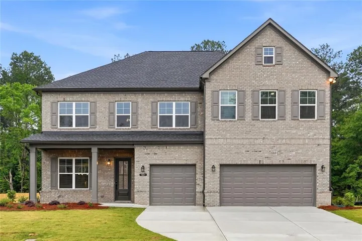 Brick exterior, covered front porch, two-car garage, and mature landscaping