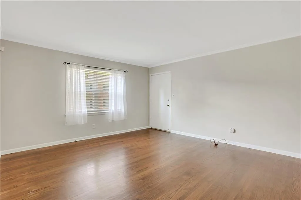Unfurnished room featuring crown molding, wood finished floors, and baseboards