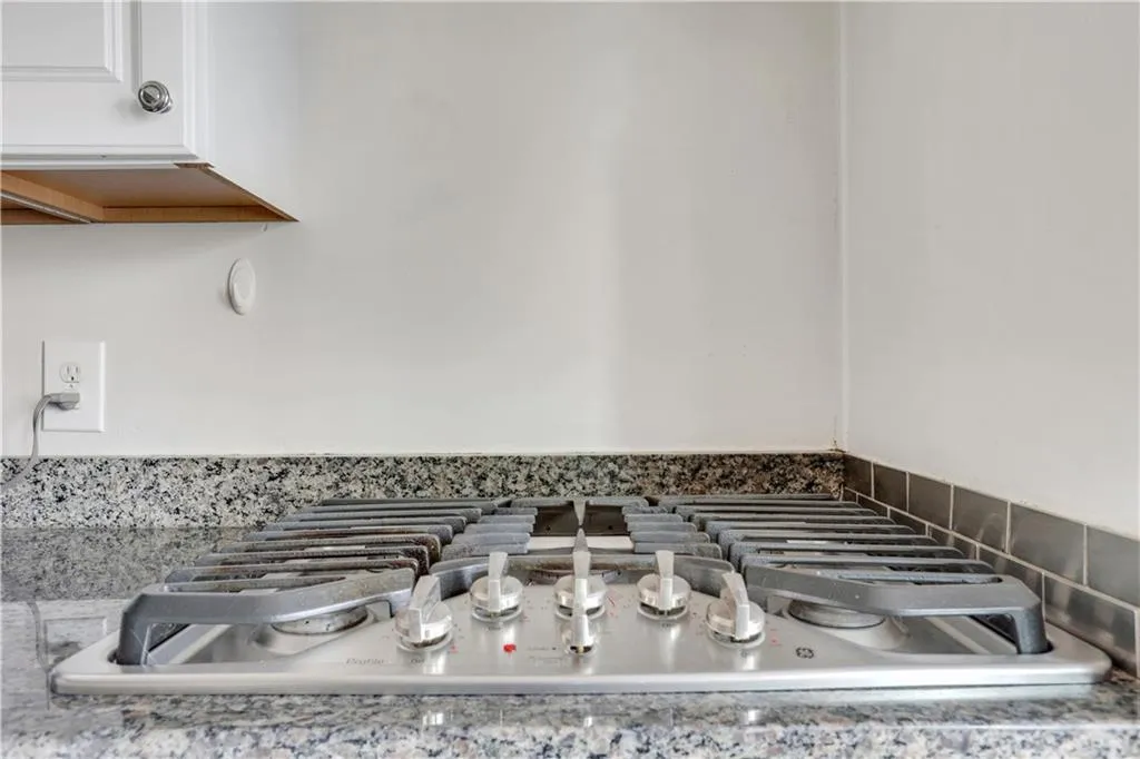 Kitchen view of stainless steel gas stovetop, white cabinetry, and light countertops